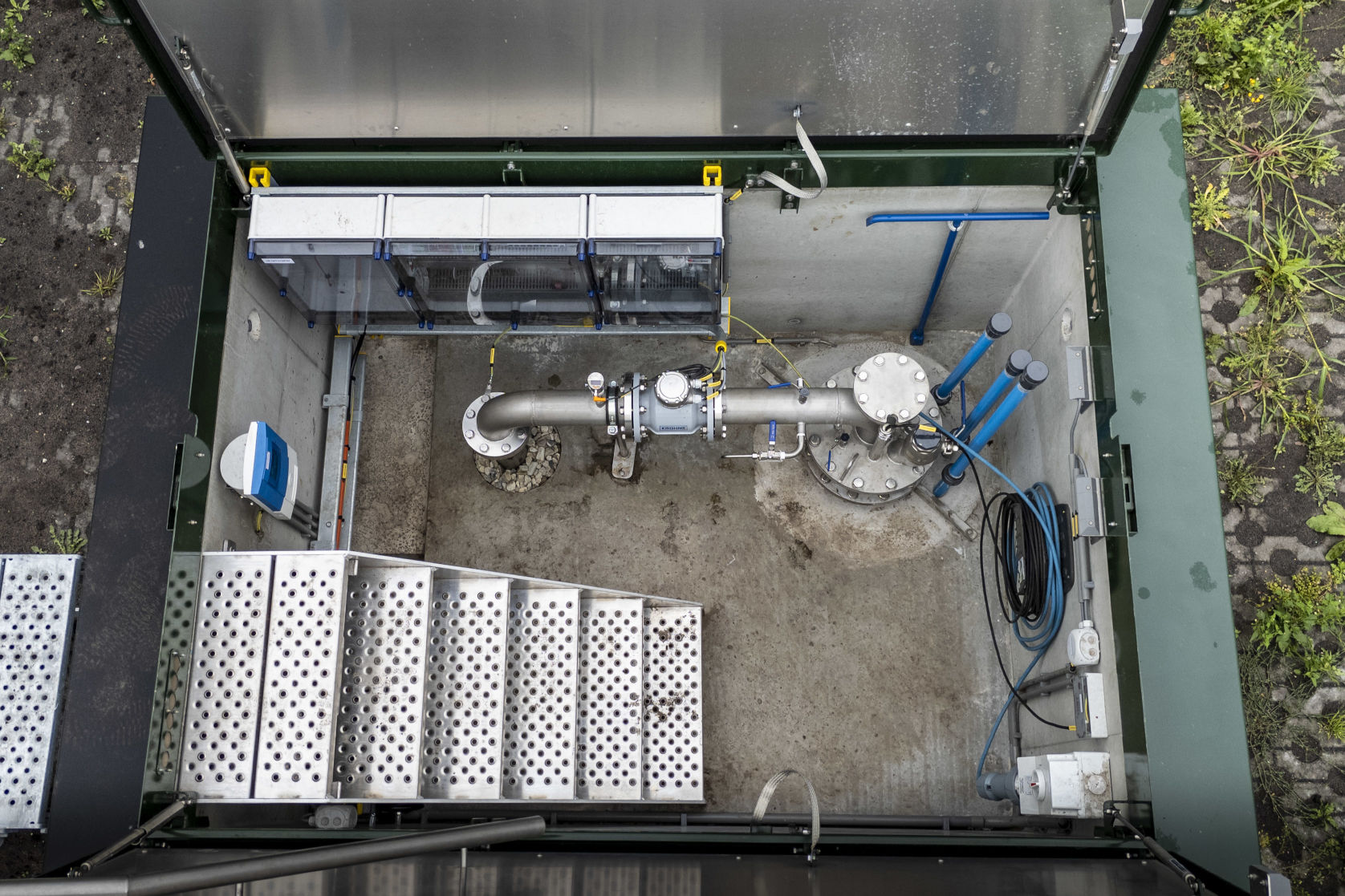 Bovenaanzicht drinkwaterput met aluminium trap en RVS leidingwerk.