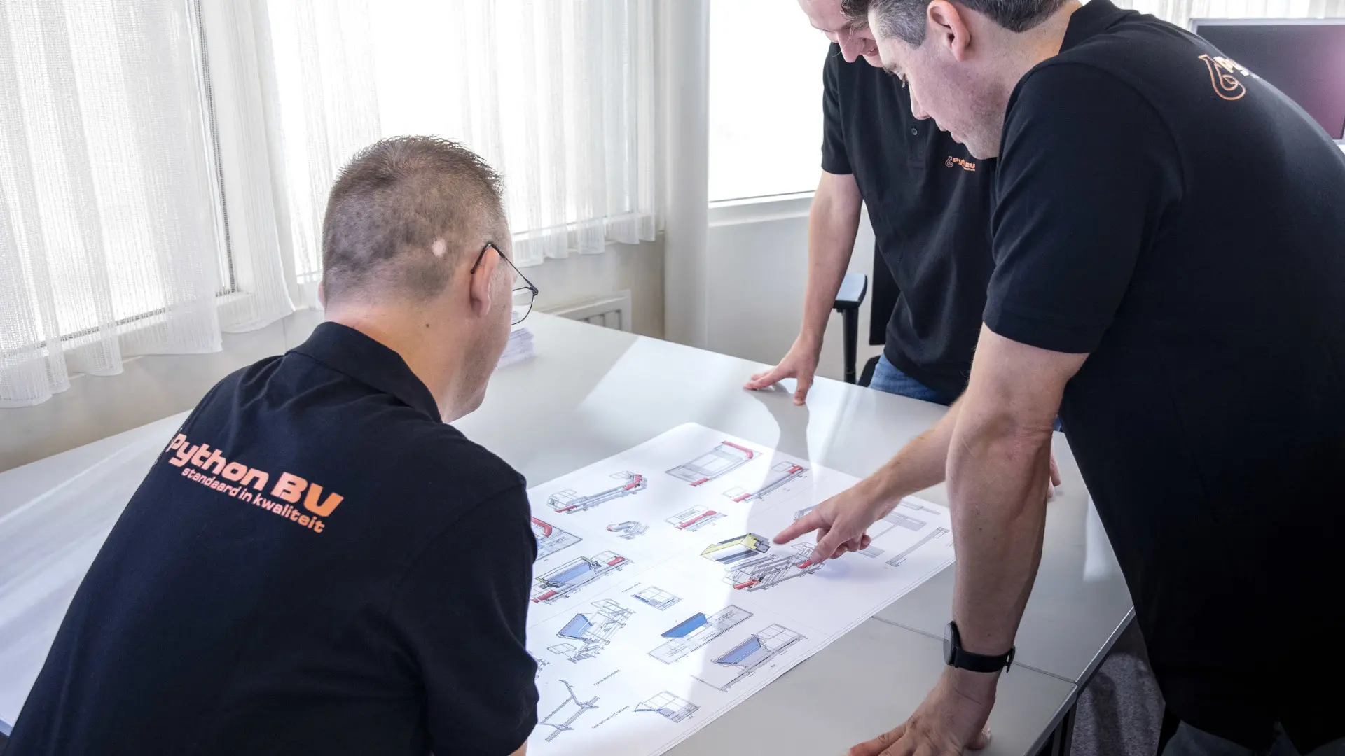 Engineers van Python buigen zich over een technische tekening.